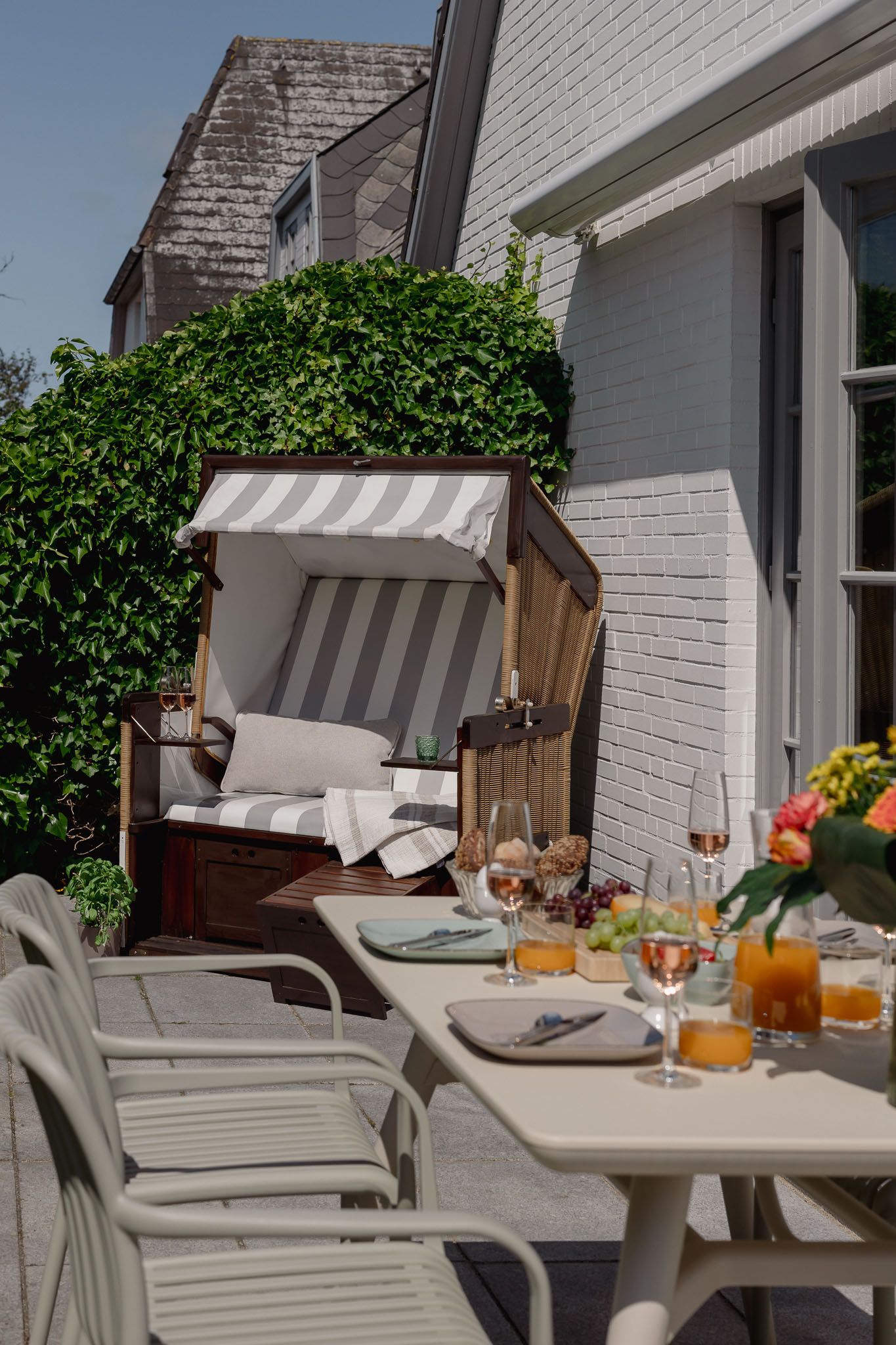 Strandkorb und gedeckter Gartentisch einer Ferienwohnung auf Sylt