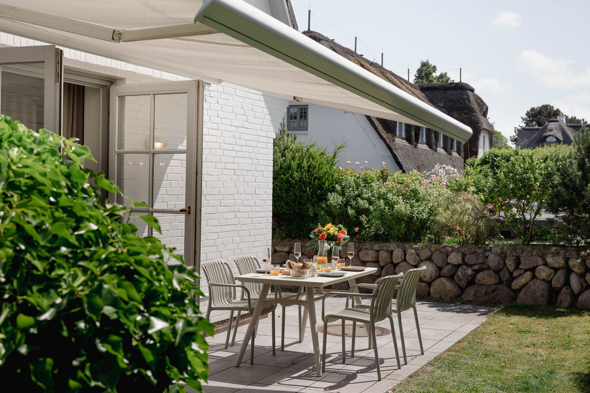 Terrasse und gedeckter Gartentisch einer Ferienwohnung auf Sylt