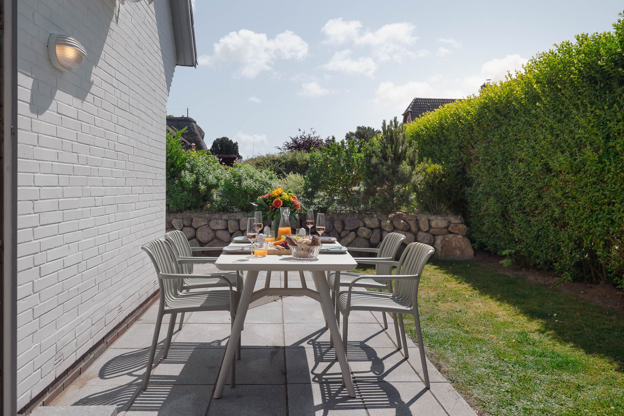Terrasse und gedeckter Gartentisch einer Ferienwohnung auf Sylt