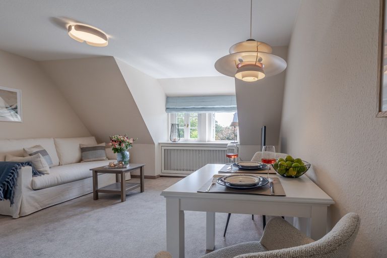 Gedeckter Esstisch und Wohnzimmer in einer Ferienwohnung auf Sylt